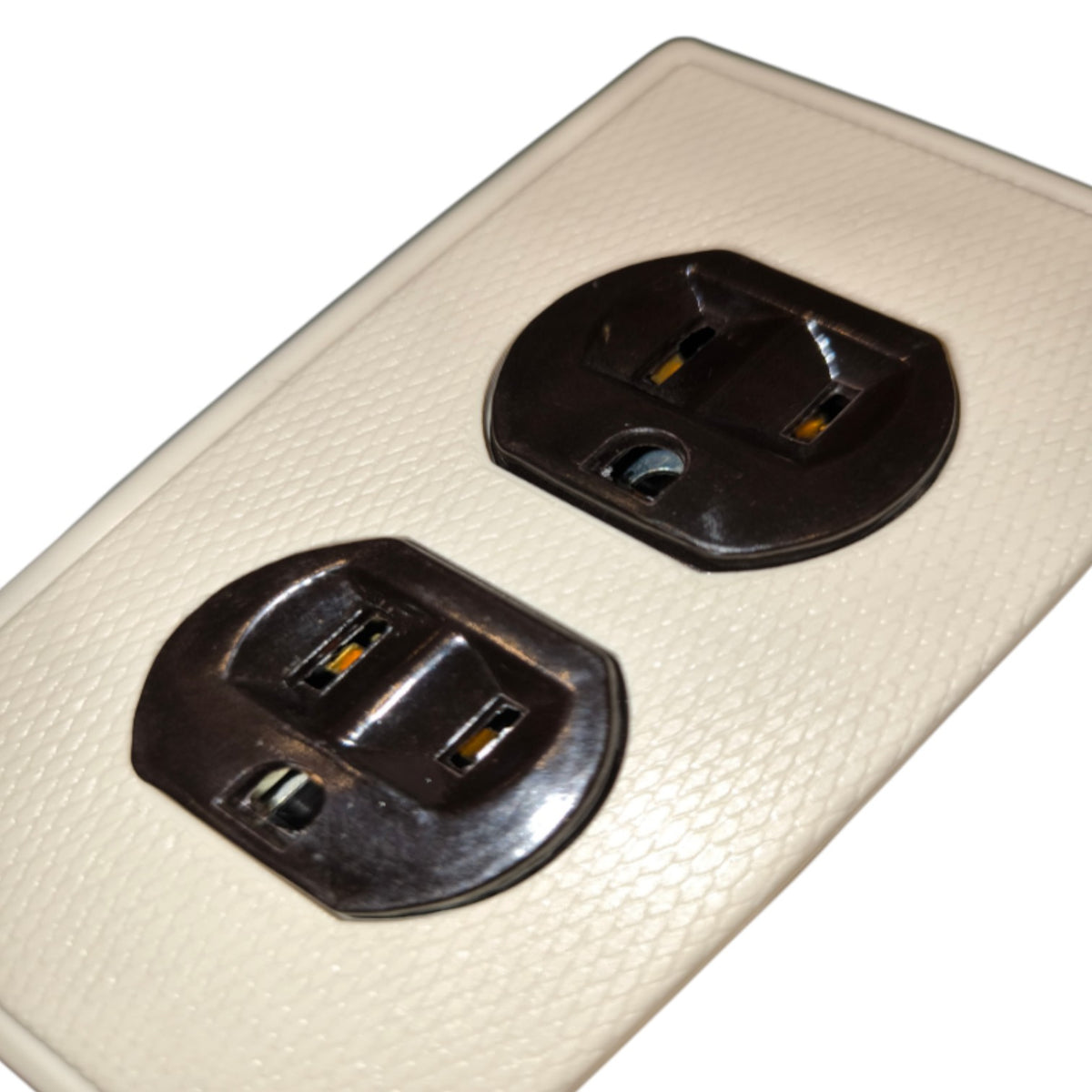 A close-up of a cream-colored textured wall outlet cover plate with two dark brown electrical outlets visible.