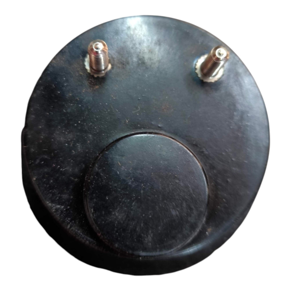 A round black plastic component, likely a sensor or cap, featuring two small metal screw posts on the top surface, shown against a plain white background.