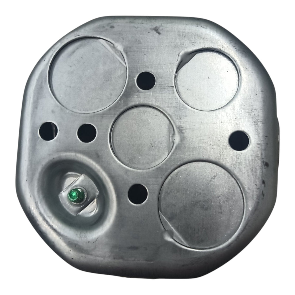 A metallic silver fuel tank lid with circular cutouts and a small green cap seal, shown against a plain white background.