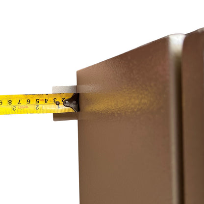 Close-up of a yellow tape measure extending horizontally against a metallic bronze panel on a white background.