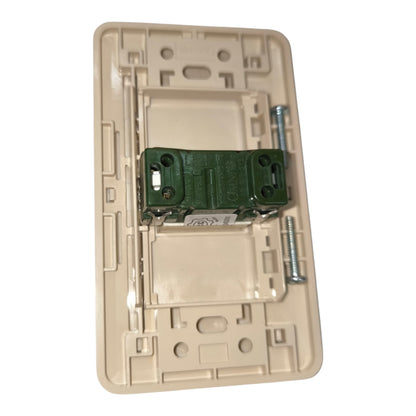 A beige plastic light switch plate backplate with a green electrical connector and mounting screws, shown on a plain white background.