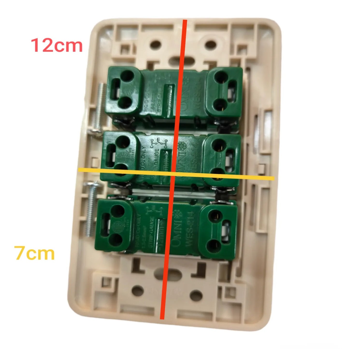 A beige wall switch plate with three green terminal blocks mounted inside, overlaid with dimension lines and text reading 12cm and 7cm to show size information.