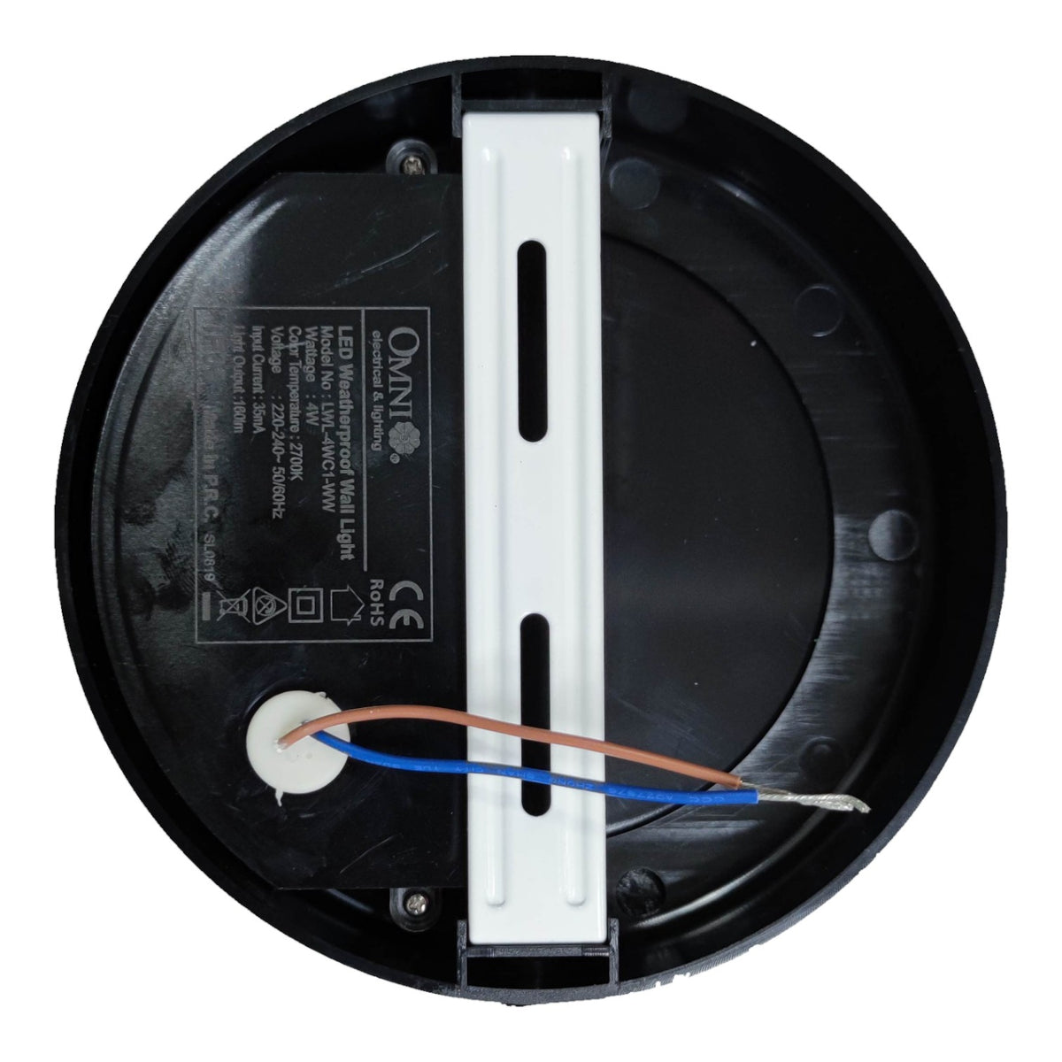 Top-down view of a circular black LED motion sensor light fixture base, showing internal wiring with blue and copper wires connected to a white terminal, and a white mounting bracket in the center.