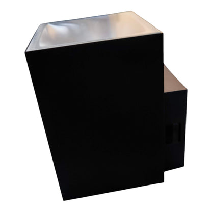 A modern black geometric wall sconce with a reflective silver top surface, shown against a plain white background.
