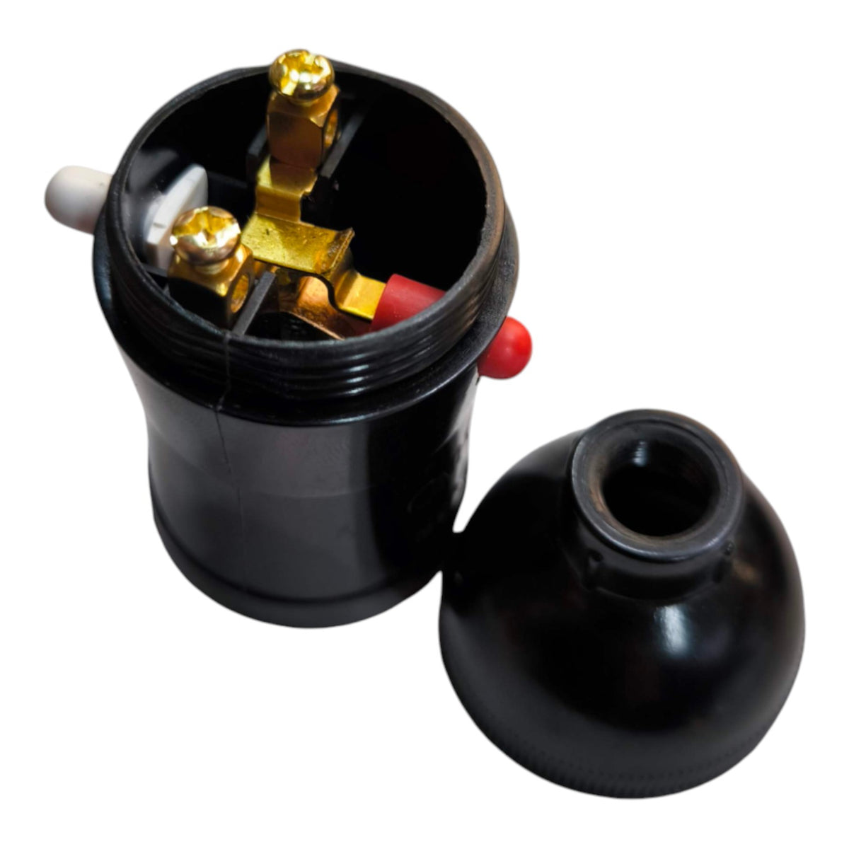 A black electrical terminal block with exposed gold-colored metal terminals and red and white internal components, shown alongside its matching black plastic cap on a white background.