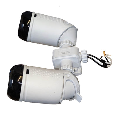 Two white dome security cameras with black lenses, connected by a central junction box with attached black and white wires, shown on a plain white background.