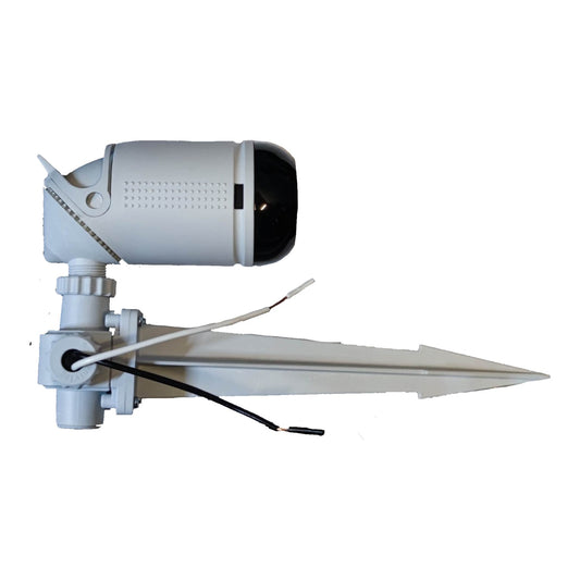 A white outdoor security camera with a ground stake mount, featuring a cylindrical camera body with a black lens cover, a mounting bracket with a pointed stake, and two wires.