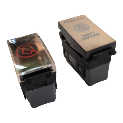 Two automotive-style toggle switches on a white background. One switch has a clear cover with a red symbol, and the other has a beige 'DON'T DISTURB' label on a black base.