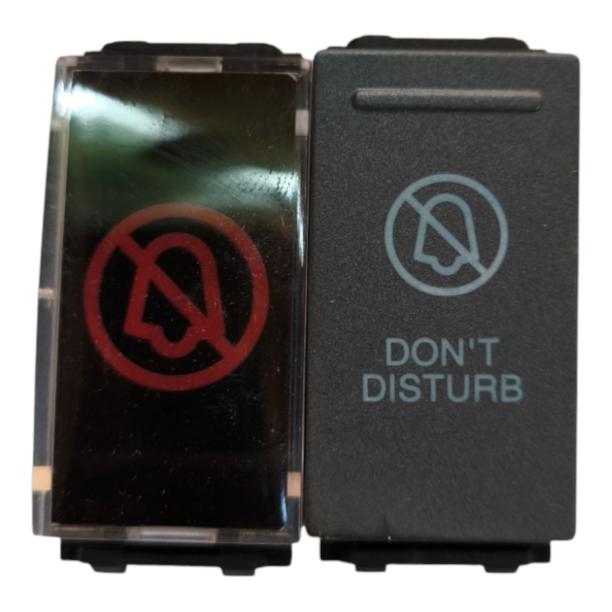 A dual-button electrical switch panel with a transparent front cover showing a red 'no bell' symbol, and a black button labeled 'DON'T DISTURB' with a gray 'no headset' symbol.