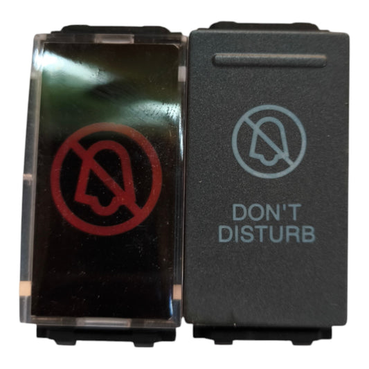 A dual-button electrical switch panel with a transparent front cover showing a red 'no bell' symbol, and a black button labeled 'DON'T DISTURB' with a gray 'no headset' symbol.