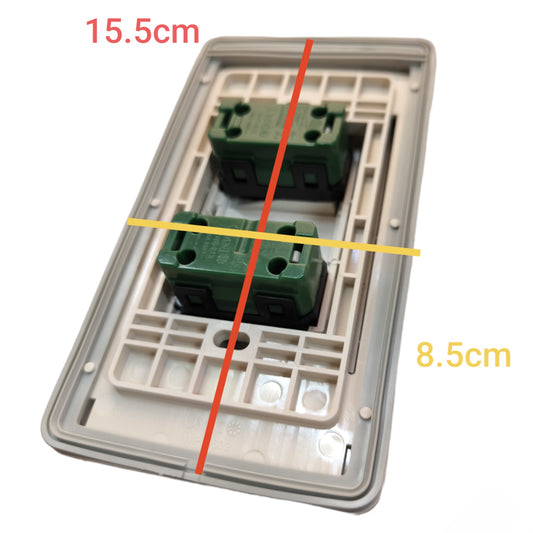 A double-gang wall switch plate with two green terminal blocks, overlaid with red and yellow measurement lines and text showing dimensions 15.5cm and 8.