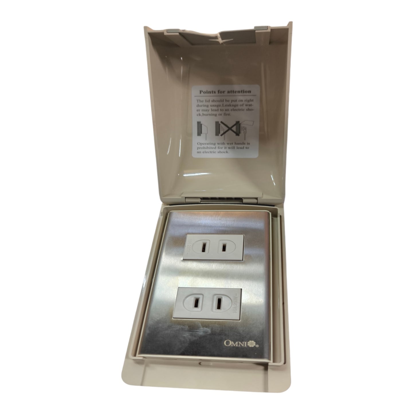 An outdoor duplex outlet cover with a stainless steel faceplate and a beige plastic hinged cover that is open, showing a warning label inside.