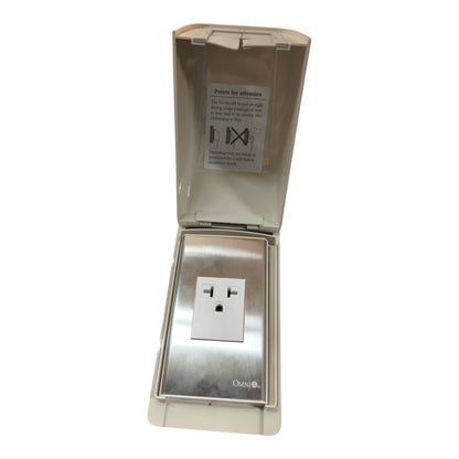 An outdoor waterproof electrical outlet cover with a stainless steel outlet inside and a translucent hinged lid, shown on a white background.