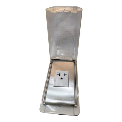 A stainless steel outdoor electrical outlet covered by a clear, weather-resistant protective hood with a hinged translucent lid, shown against a plain white background.