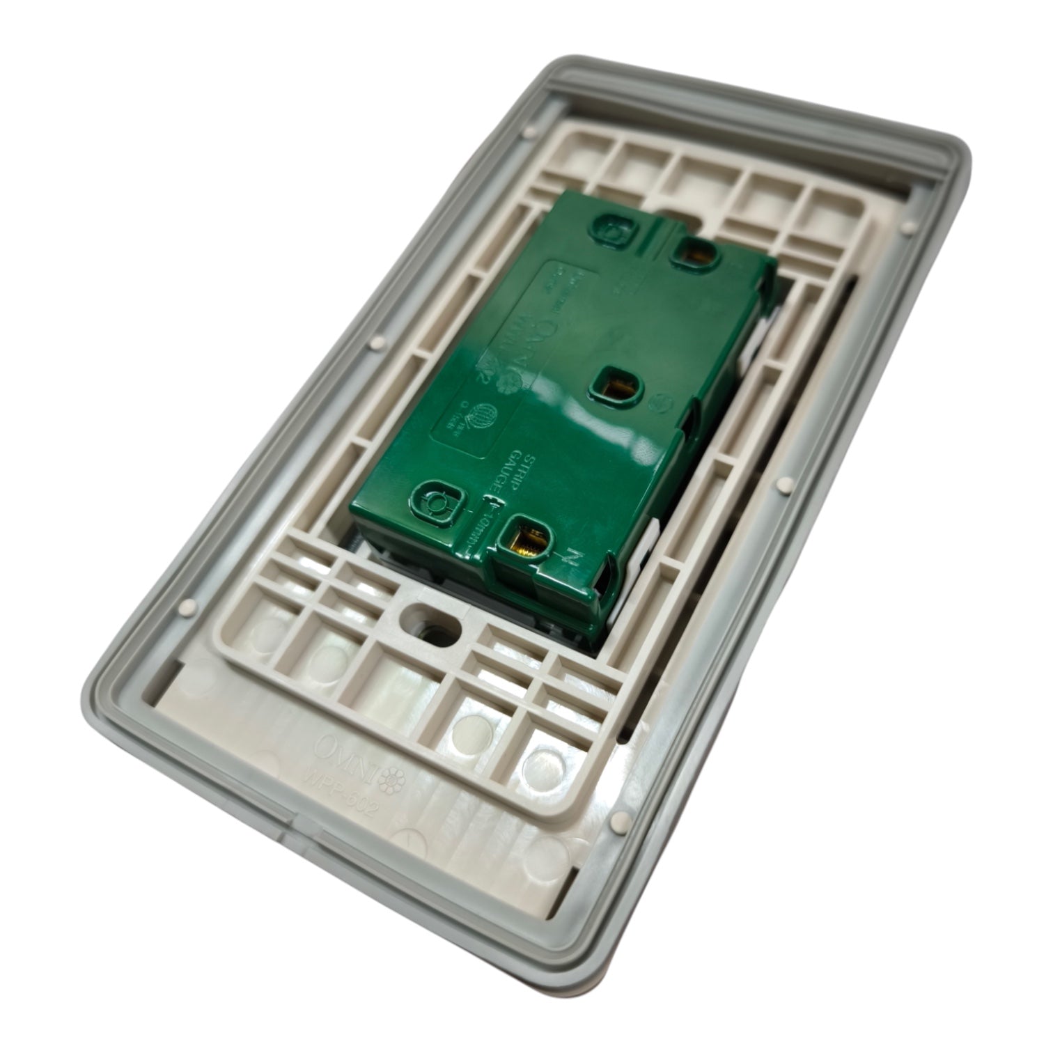 A close-up of a wall switch module showing the green main terminal board and the beige plastic backplate.