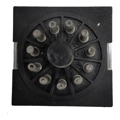 A black circular multi-pin electrical connector or terminal block with a central round knob and multiple small metal pins radiating outward, shown on a plain white background.