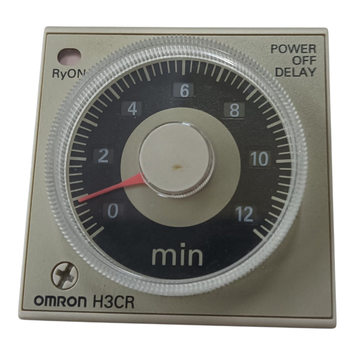 An Omron H3CR 12-minute analog timer dial with a beige metal casing, black face, white markings, and a red pointer needle.