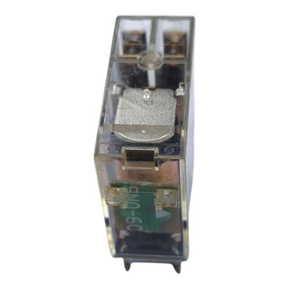 A small transparent plastic electrical relay component with internal copper-colored coils, a silver metal plunger, and green circuitry visible inside, isolated on a white background.