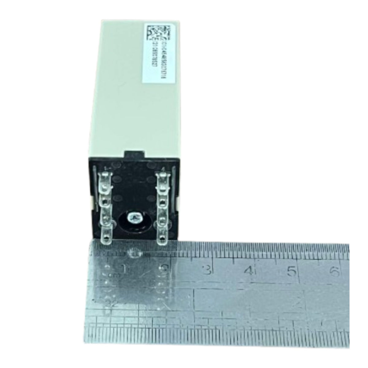 A small rectangular electronic component with a light beige top and black front, shown next to a metal ruler for scale on a white background.