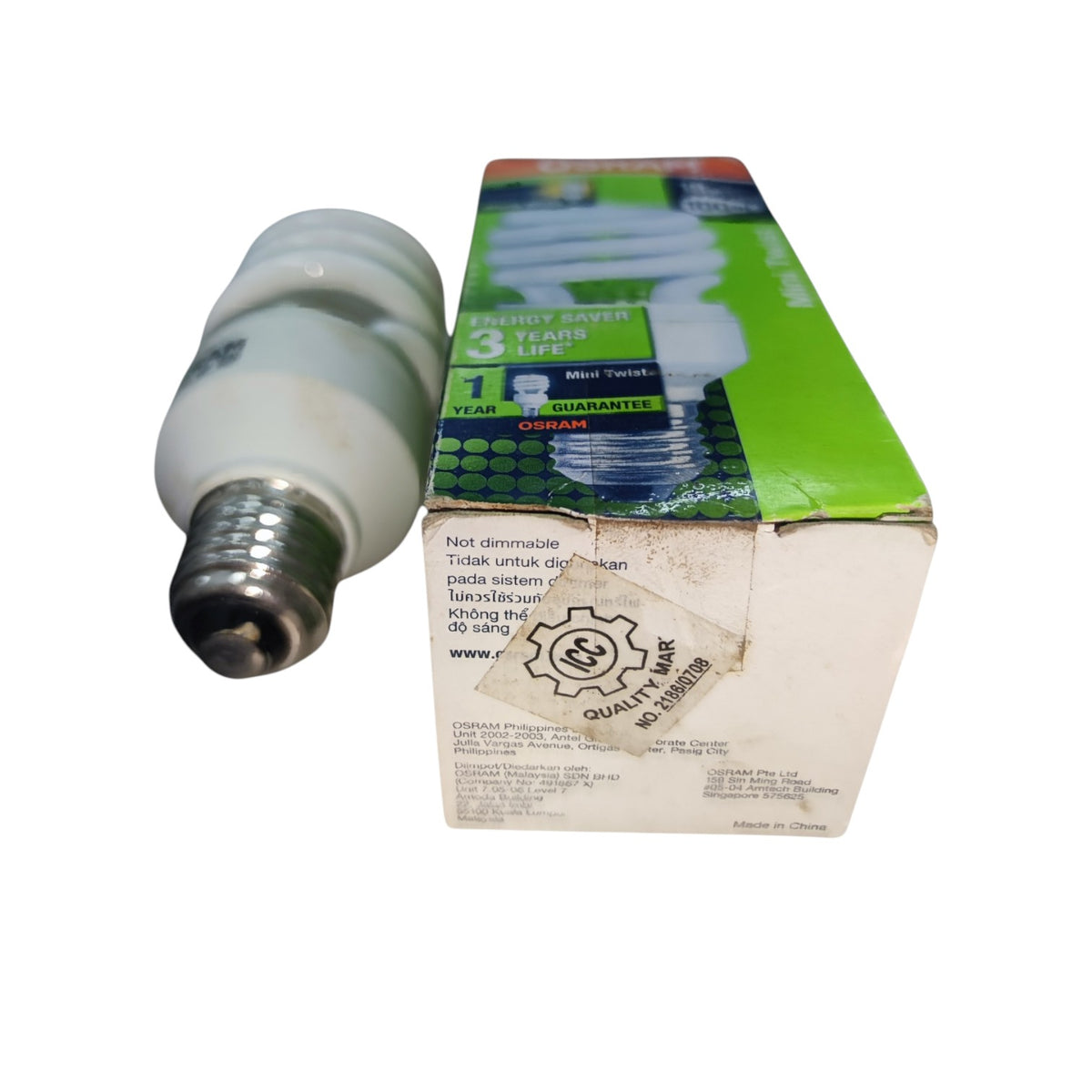 A compact fluorescent light bulb with a screw base shown next to its retail packaging box on a plain white background.