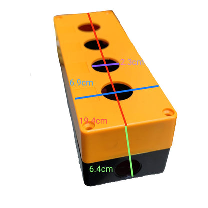 A rectangular orange and black plastic block with four circular holes on top, overlaid with colored measurement lines and labels showing dimensions in centimeters.
