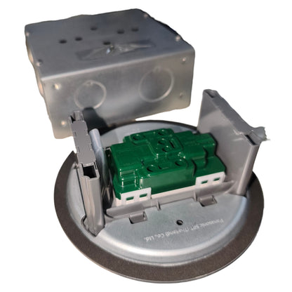 A circular metal electrical component with a green plastic module in the center, shown with its upper metal cover removed and set against a plain white background.