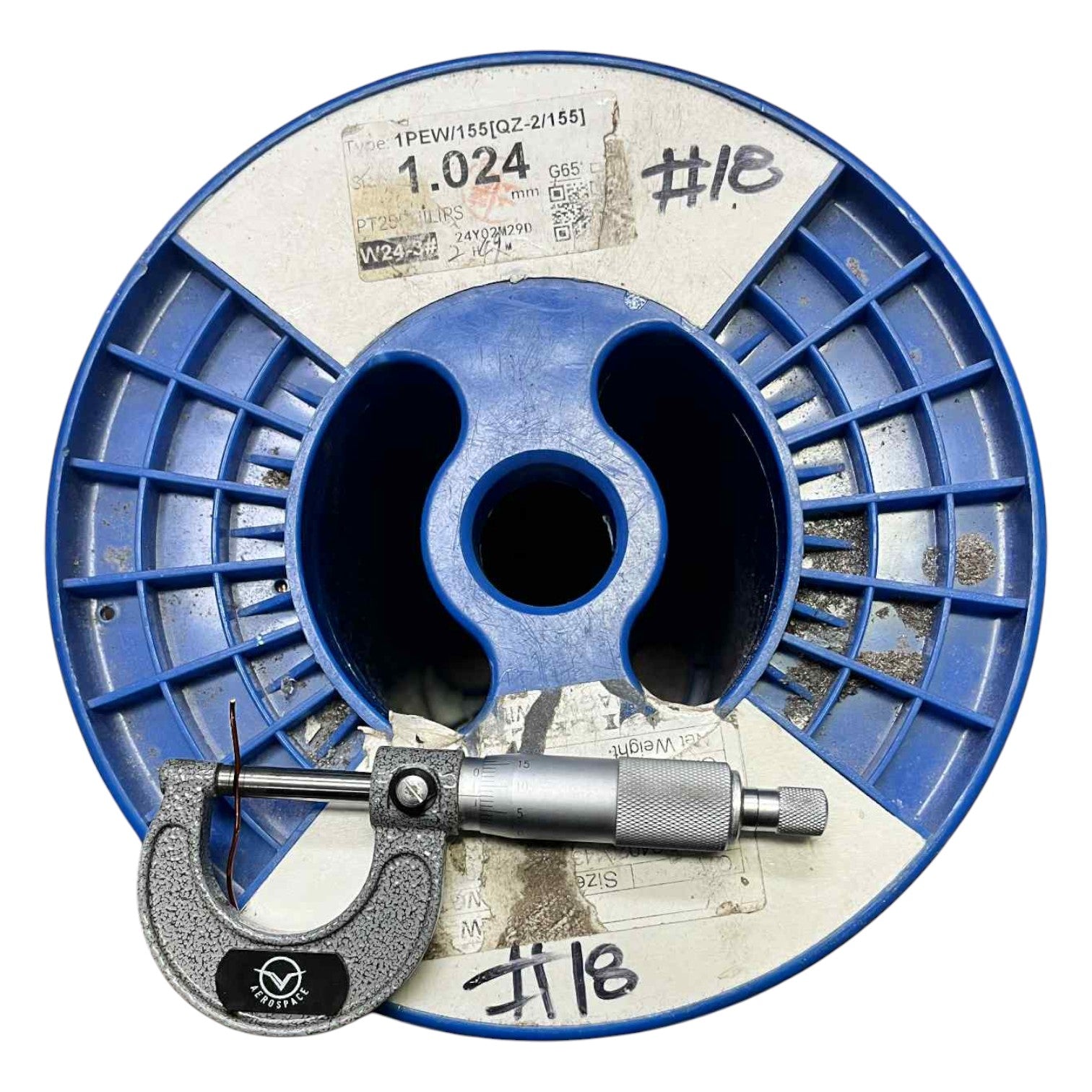 Blue spool of wire with a micrometer on a white background