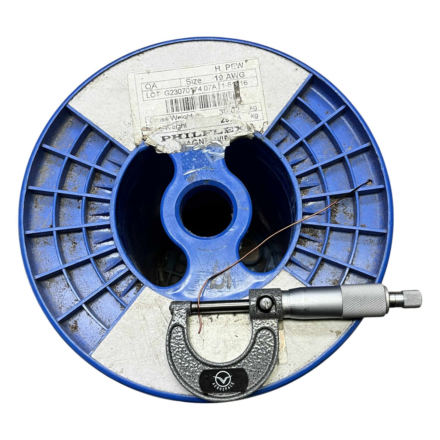 Blue spool of thread with a micrometer on a white background