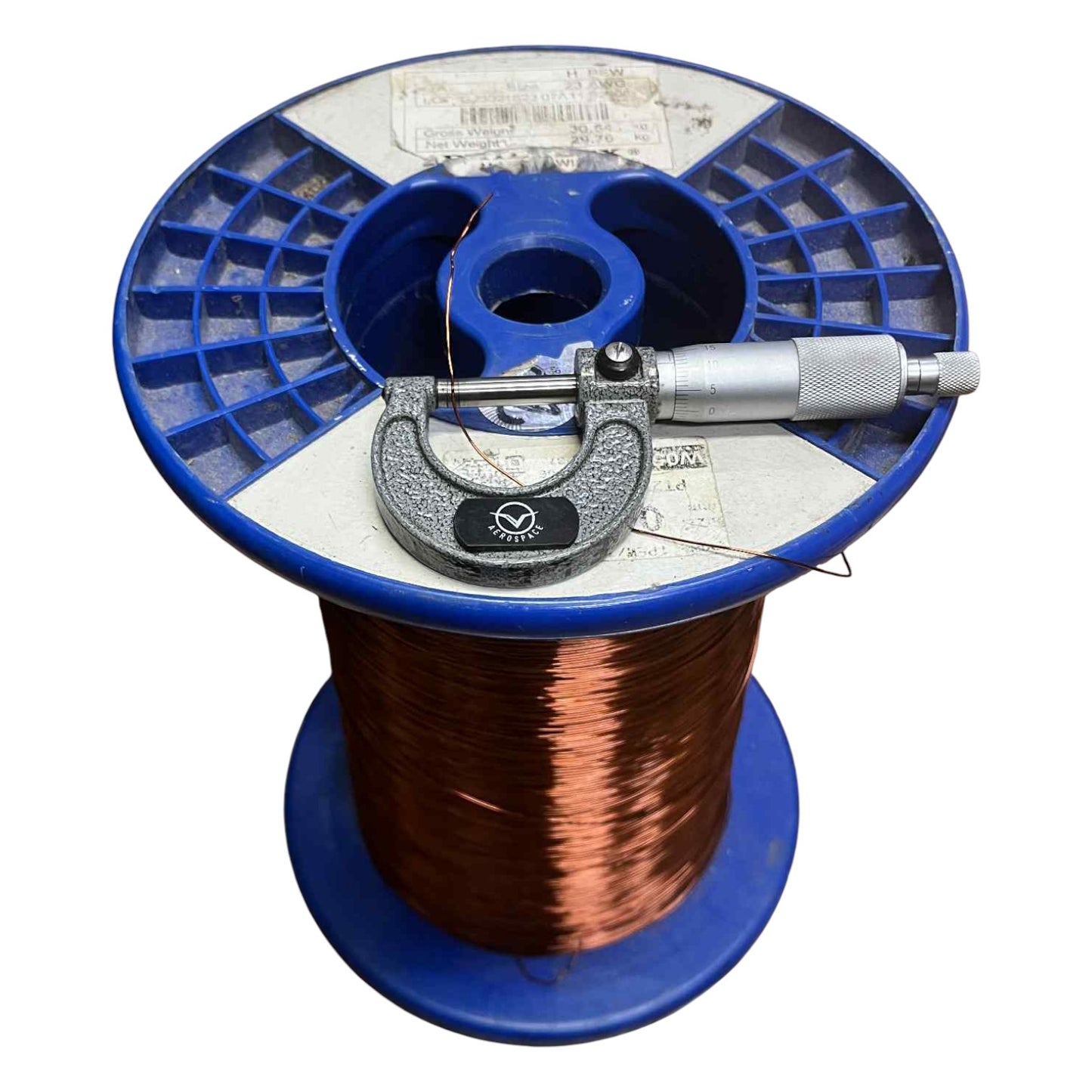 Spool of copper wire with a blue reel and micrometer on a white background