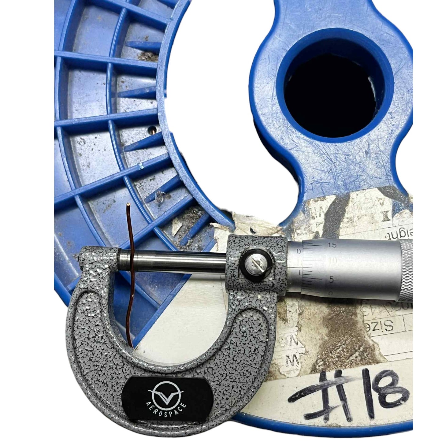 Micrometer on a white background with blue tool in the background