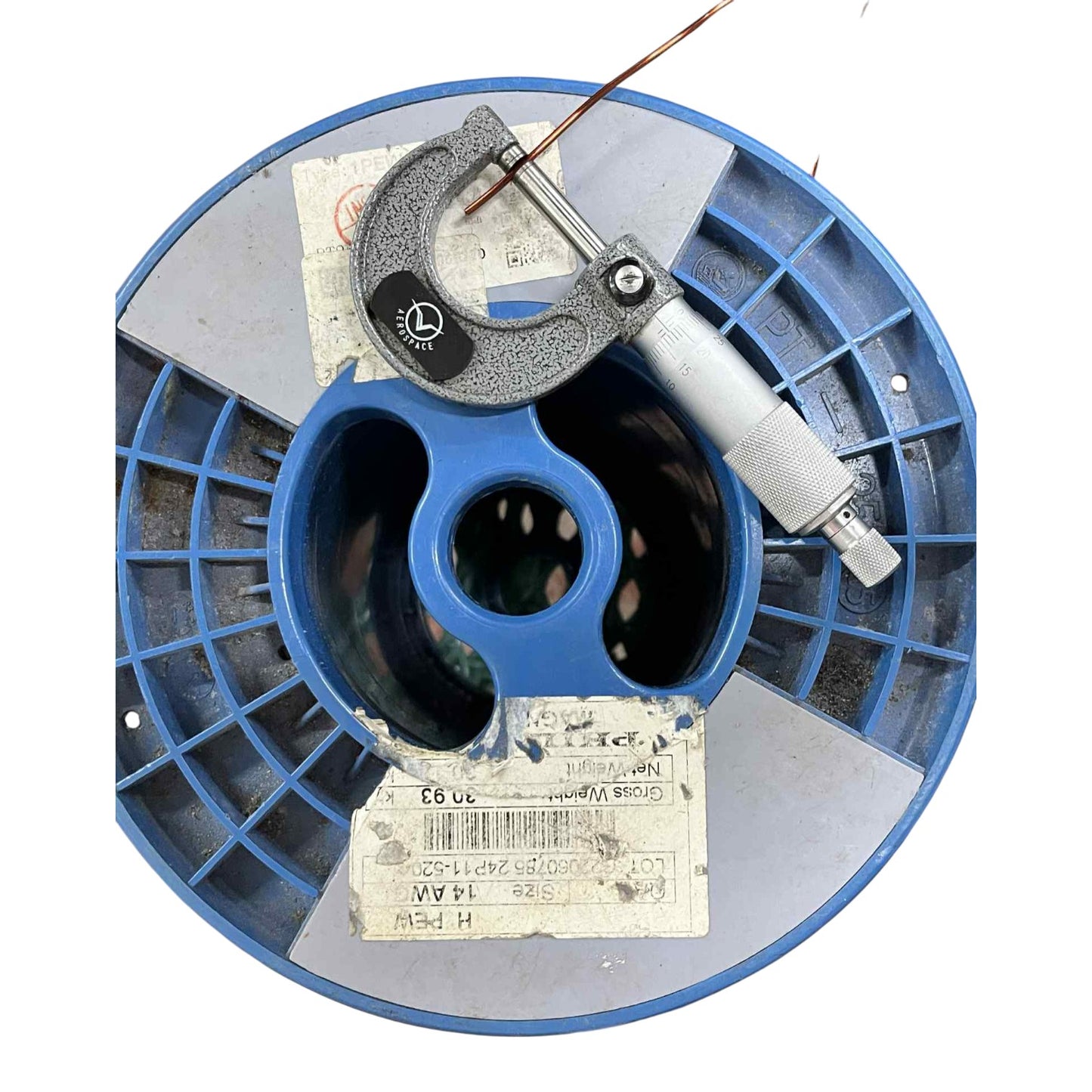 Blue spool with a micrometer on top against a white background