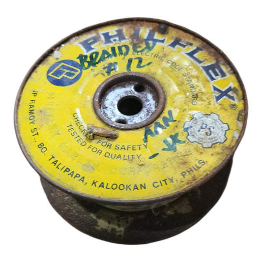A vintage yellow Phil-Flex brand electric code swivel braided rope spool, showing rusted metal edges and handwritten markings on the top surface.