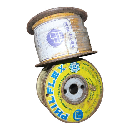 Two spools of Philflex brand electrical cord, stacked vertically. The top spool contains yellowed, weathered cord with a white paper label featuring the blue Philflex logo.