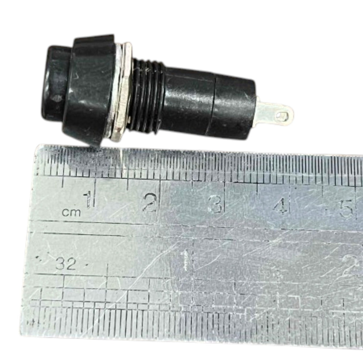 A small black electrical push-in connector with a metal terminal, shown next to a metal ruler for scale on a white background.