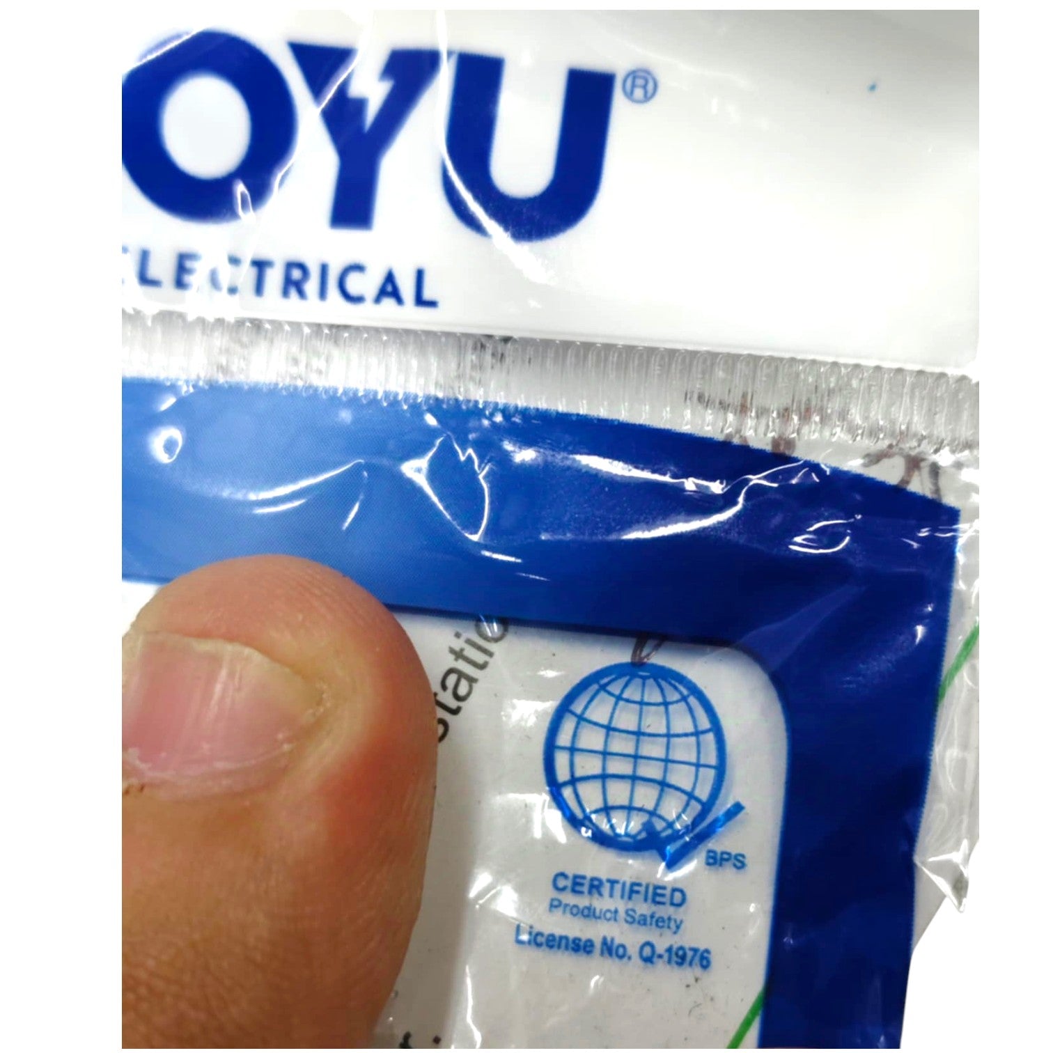 A close-up of a packaged OYU Electrical electrical component, showing a blue and white plastic sleeve with a finger covering part of the front label.