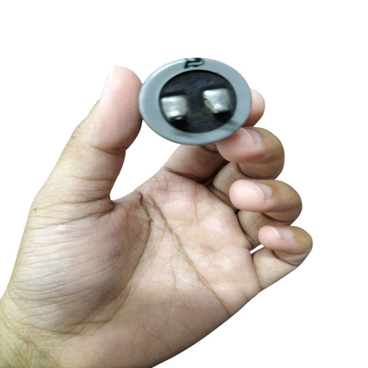 SH running capacitor for Motor held in hand, showcasing its compact design and electrical connections