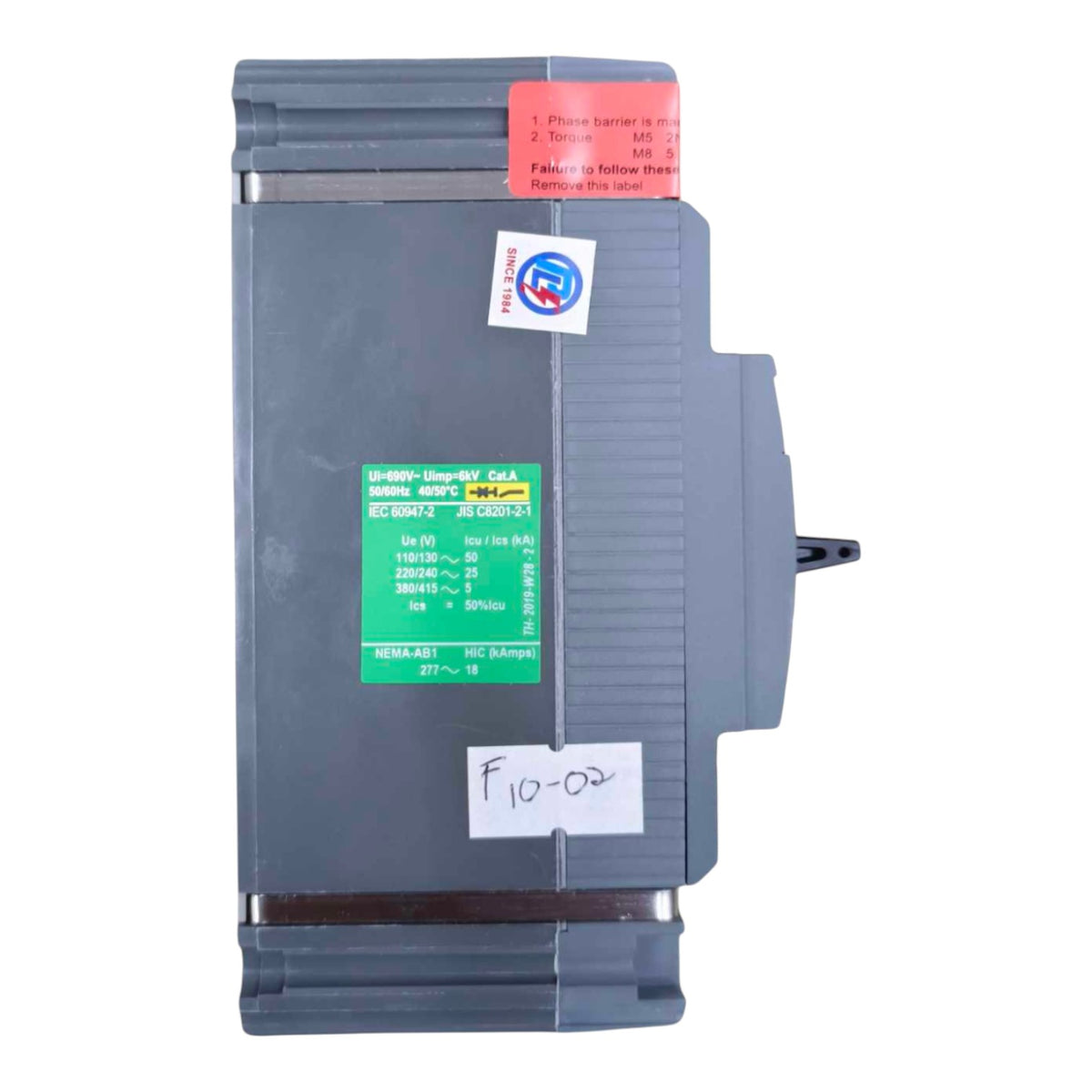 A Siemens industrial electrical module, model 6ES7 2-EX2 430-4600-01, in gray plastic with a green and white technical label, a red warning sticker, and a white handwritten label.