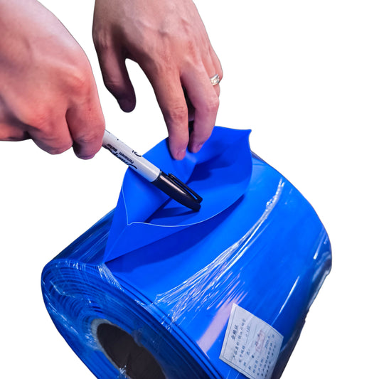 Person using a marker to write on a roll of blue vinyl wrap.