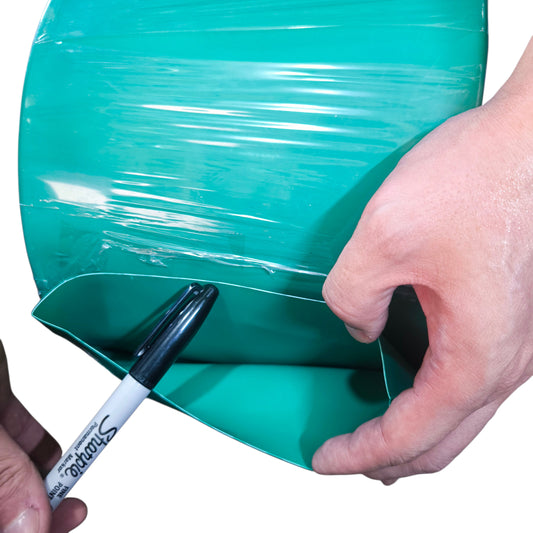 Person using a marker to draw on a roll of green cellophane.