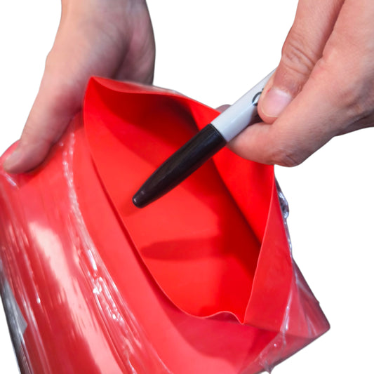 Person using a marker to write on a red object with a white background