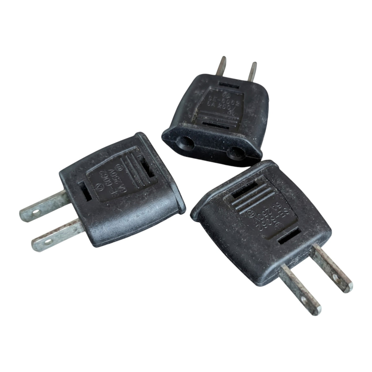 Three black plastic US plug adapters with silver metal pins, arranged on a plain white background.