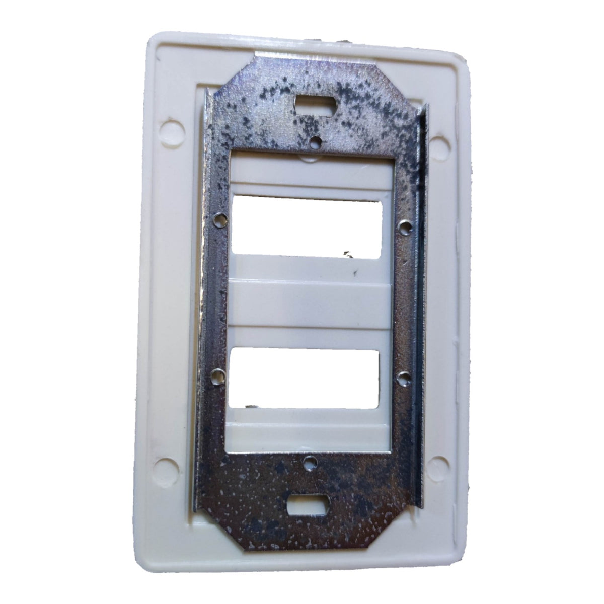 A white plastic double-gang outlet cover plate with a rusty metal mounting bracket attached inside, shown against a plain white background.