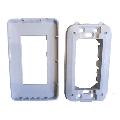 Two white plastic electrical outlet or switch plate frames shown on a plain white background, one with a rectangular center cutout and one with a different shaped cutout and mounting holes.