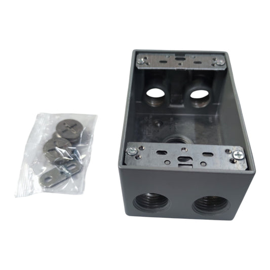 A dark gray metal electrical junction box with threaded ports on the front, shown alongside a small clear plastic bag containing mounting screws and washers on a white background.