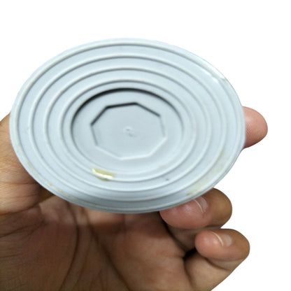 Hand holding a 4MFD motor running capacitor showcasing its circular design and size