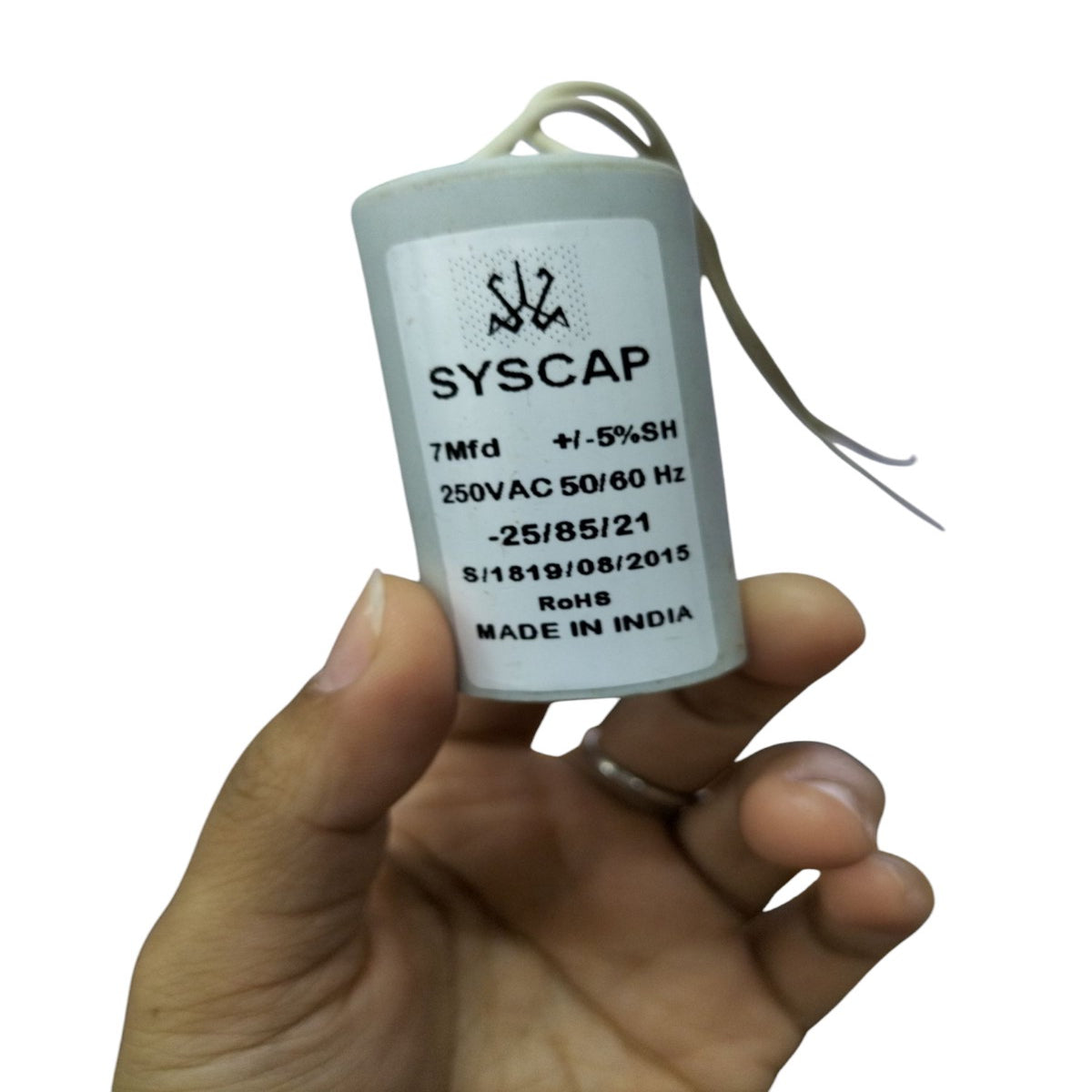 Hand holding a Syscap 7 Microfarad AC Motor Capacitor for electrical circuitry and parts