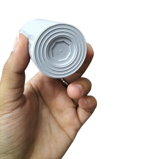 Hand holding Syscap electrical capacitors for motors with a white cylindrical body