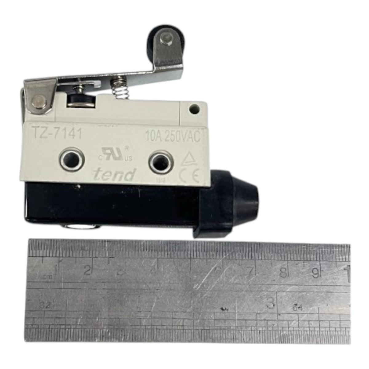 A small industrial electrical switch component with a white top plate, black base, and metal lever, shown next to a metal ruler for scale on a white background.