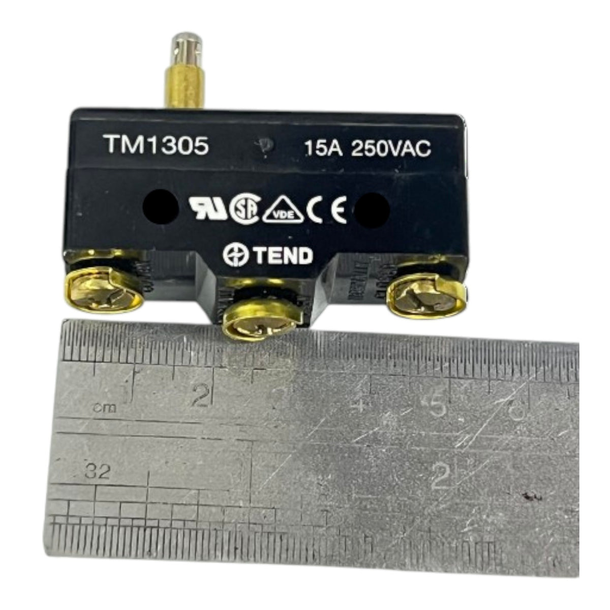 A black TEND TM1305 15A 250VAC thermal switch with gold-colored screw terminals and a small gold terminal stem, shown above a metal ruler for scale on a white background.