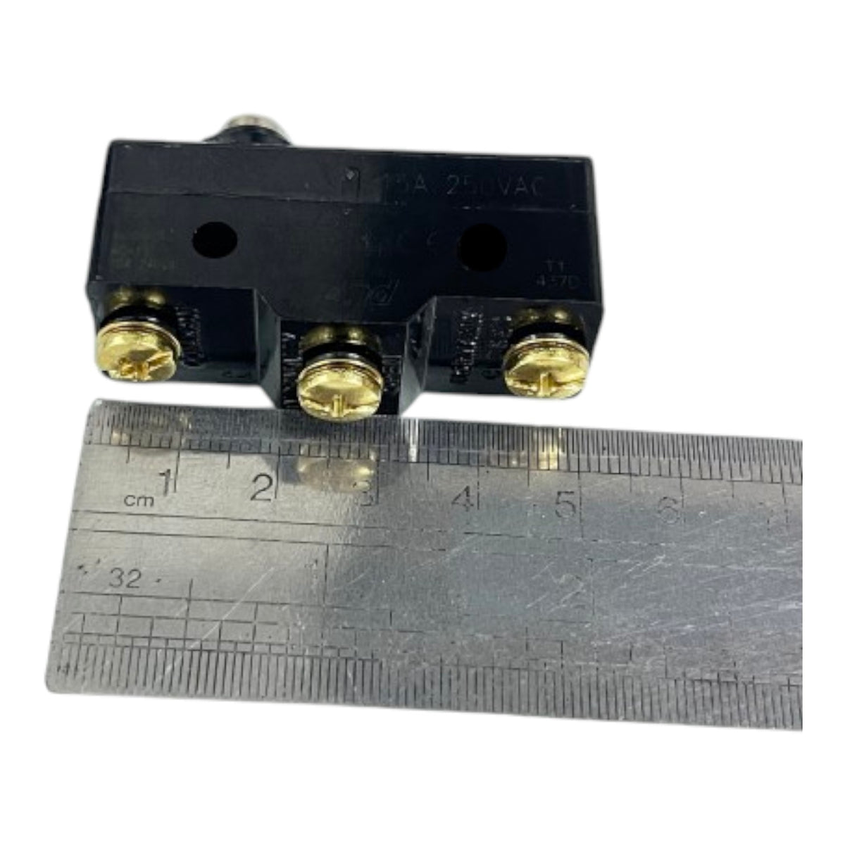 A small black electrical component with three gold screw terminals, shown above a metal ruler for scale on a white background.
